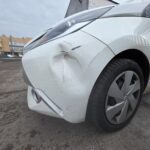 White Toyota with front corner collision damage in the Linwood Coachworks yard, Paisley